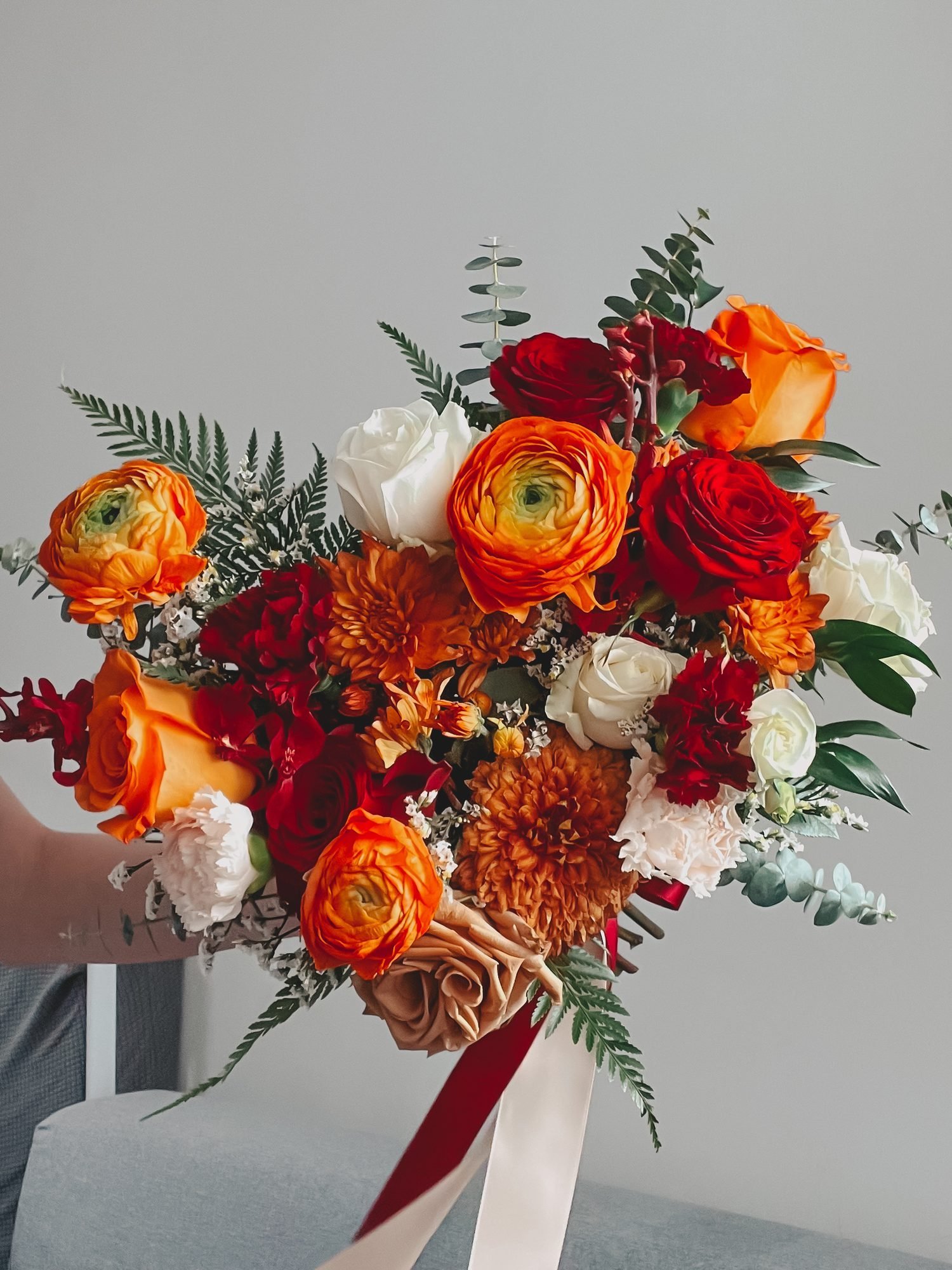 Liz dramatic · asymmetrical bridal bouquet in tangerine, crimson, blush, ivory and sage — close-up