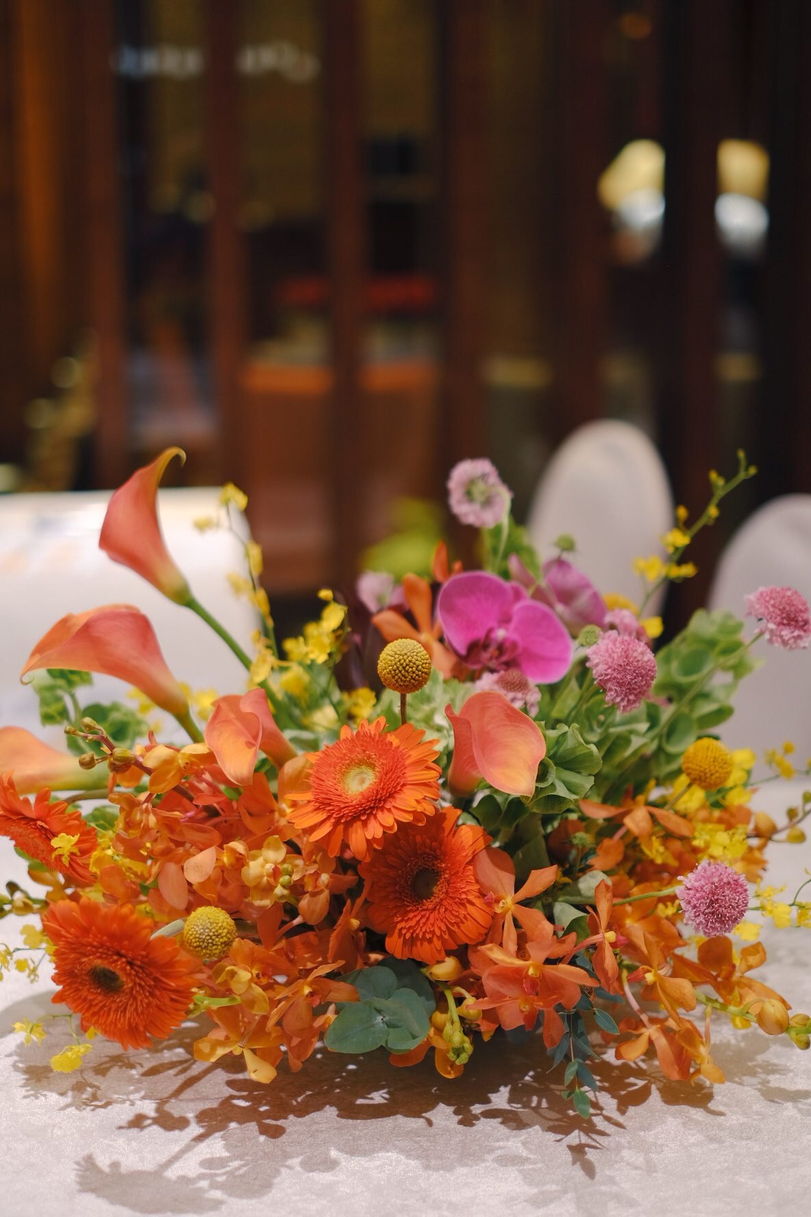 Close-up of a bright orange, fuchsia and yellow reception table arrangement