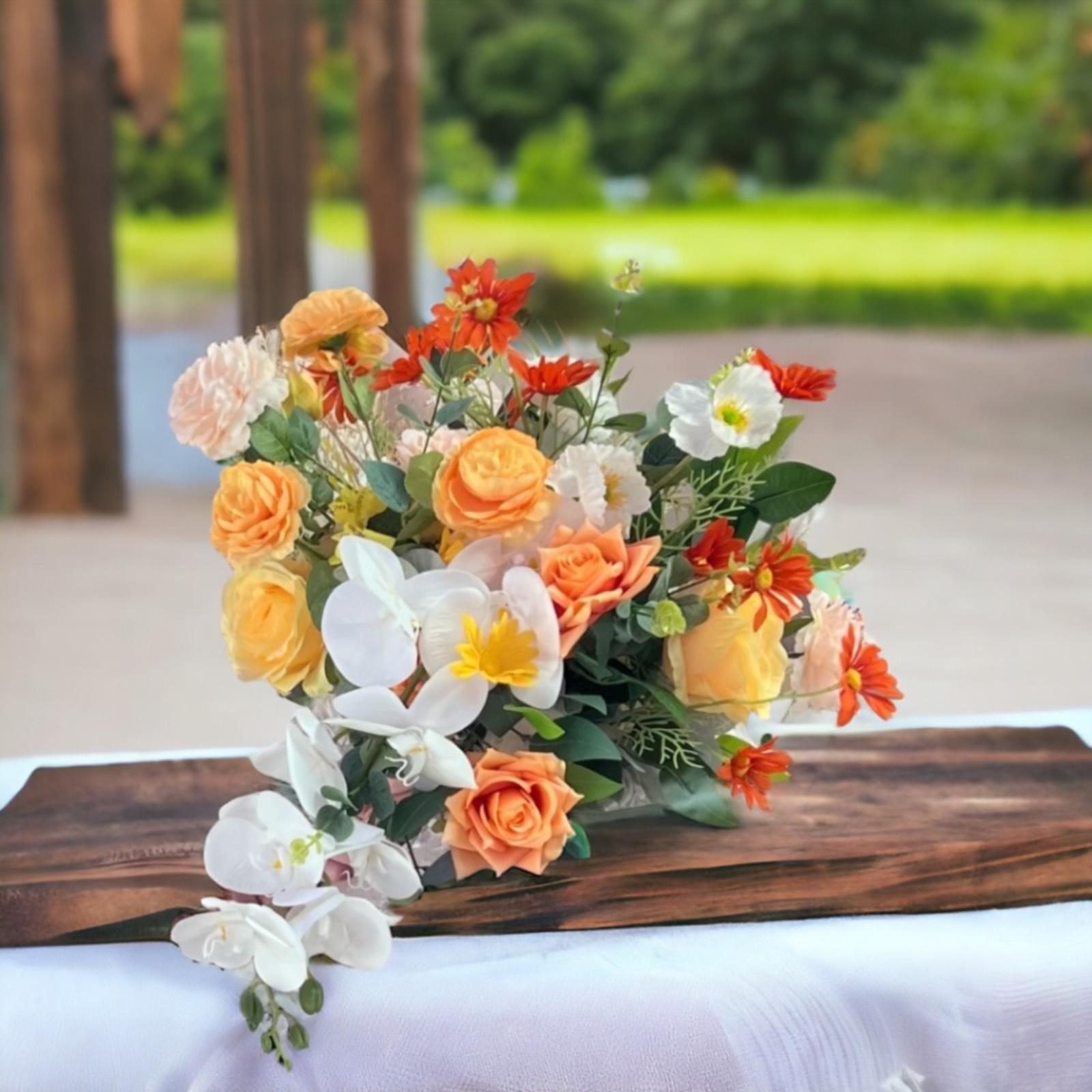 Bouquet of orange, yellow and cream roses with white orchids trailing over a wooden board