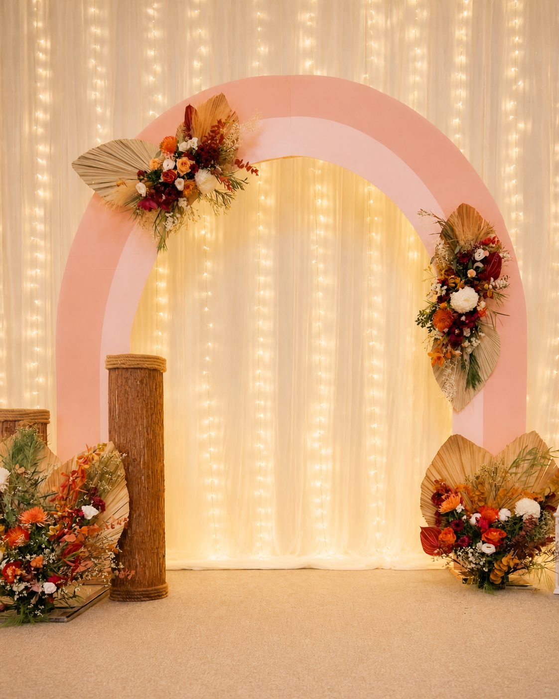 Blush double-arch backdrop with fairy lights, dried palm fronds and rust floral clusters