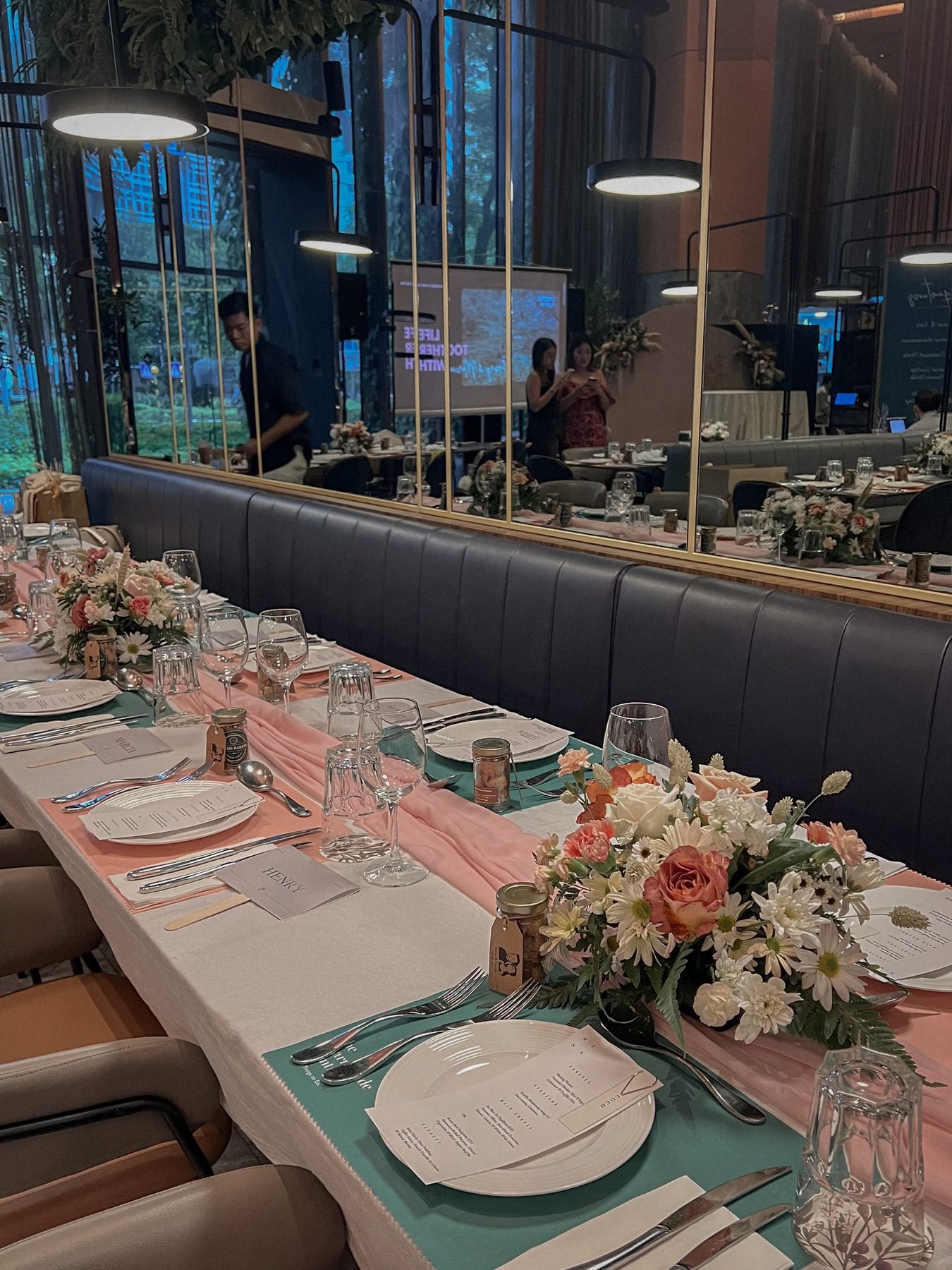 Long banquet dining table set with small pink and white floral centres and pink runners