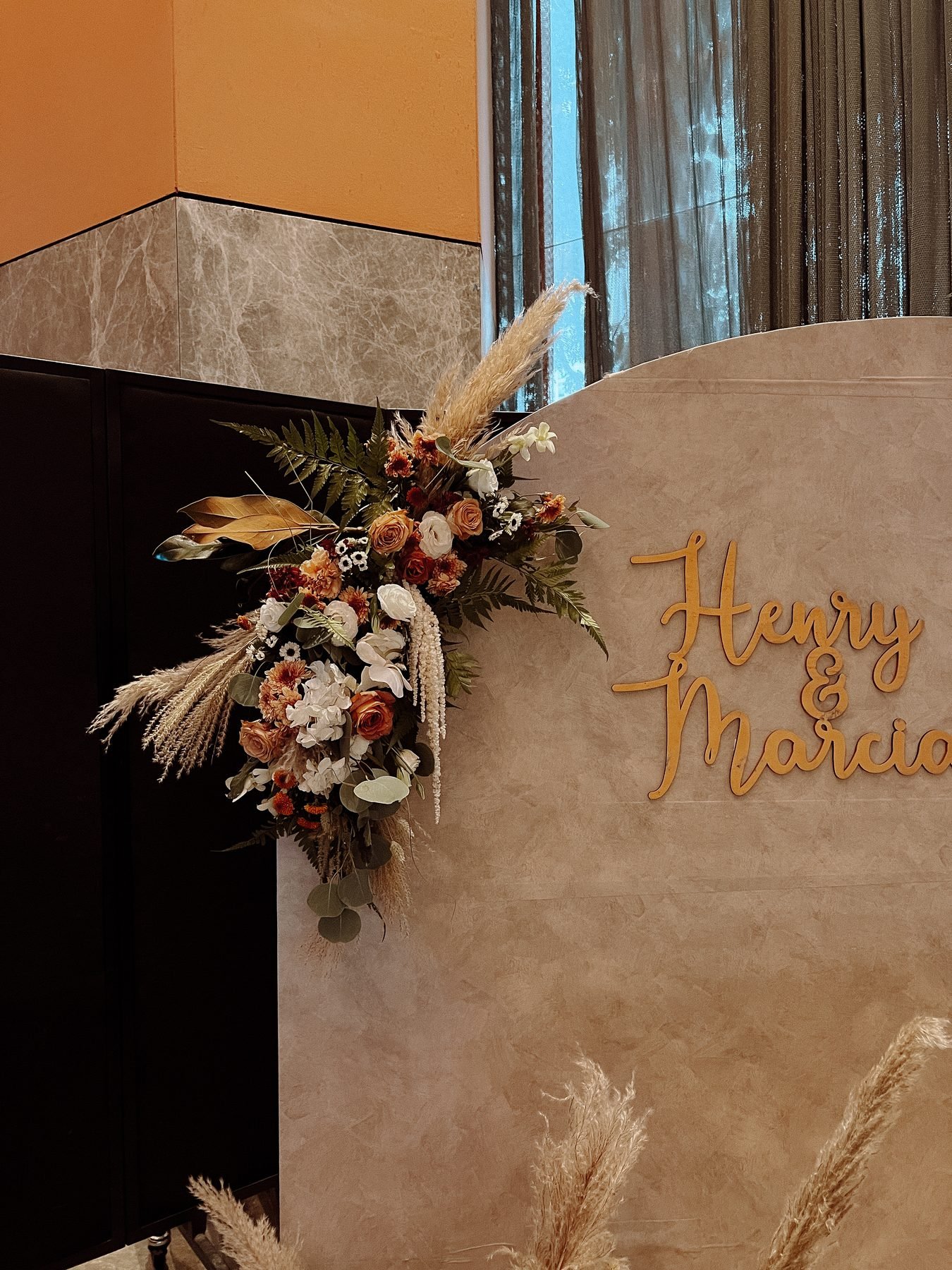 Close detail of a trailing floral corner of rust, ivory and pampas grass against a taupe backdrop