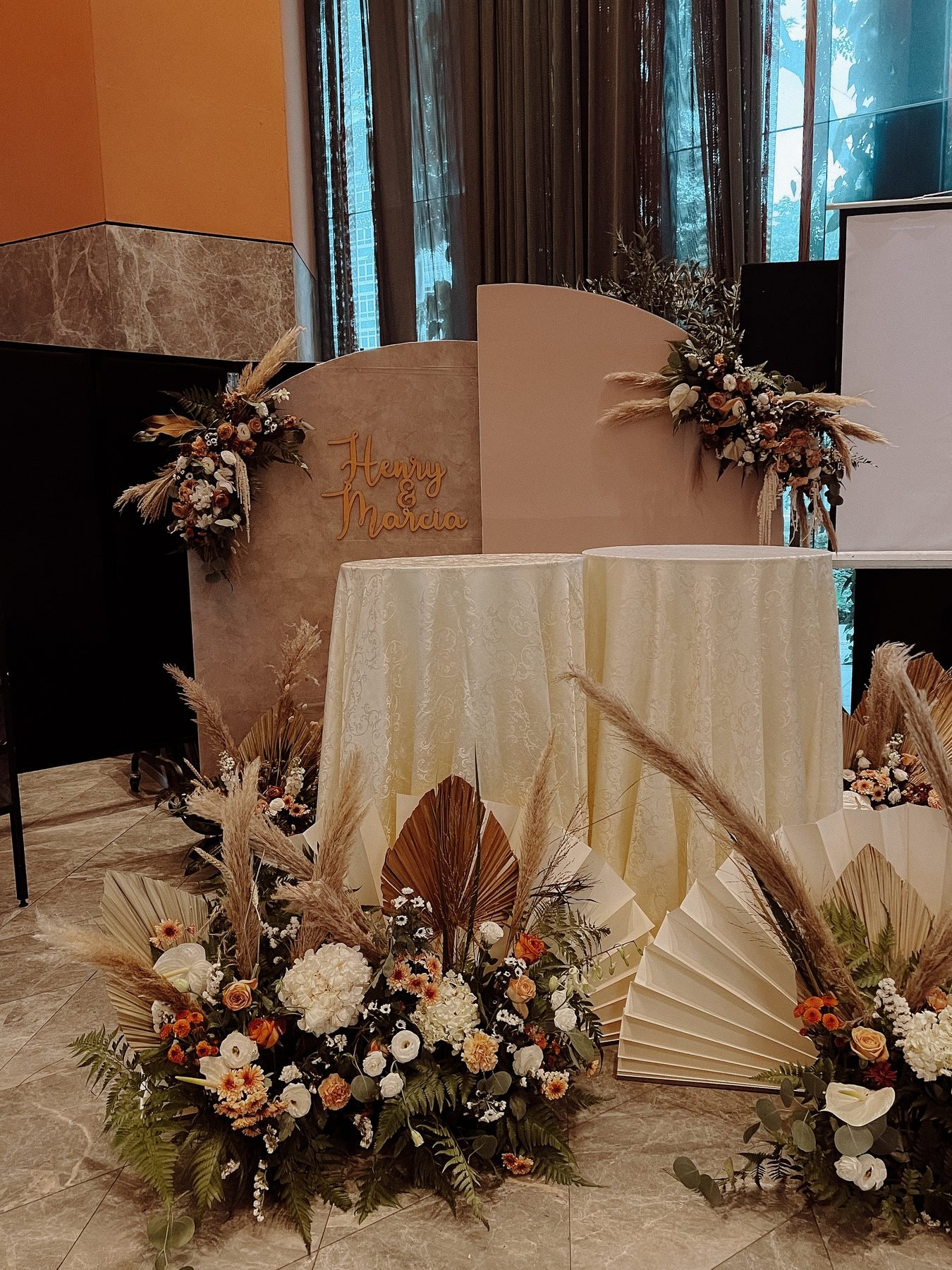 Welcome backdrop with two round tables and floor florals of pampas, dried palms and warm-toned blooms