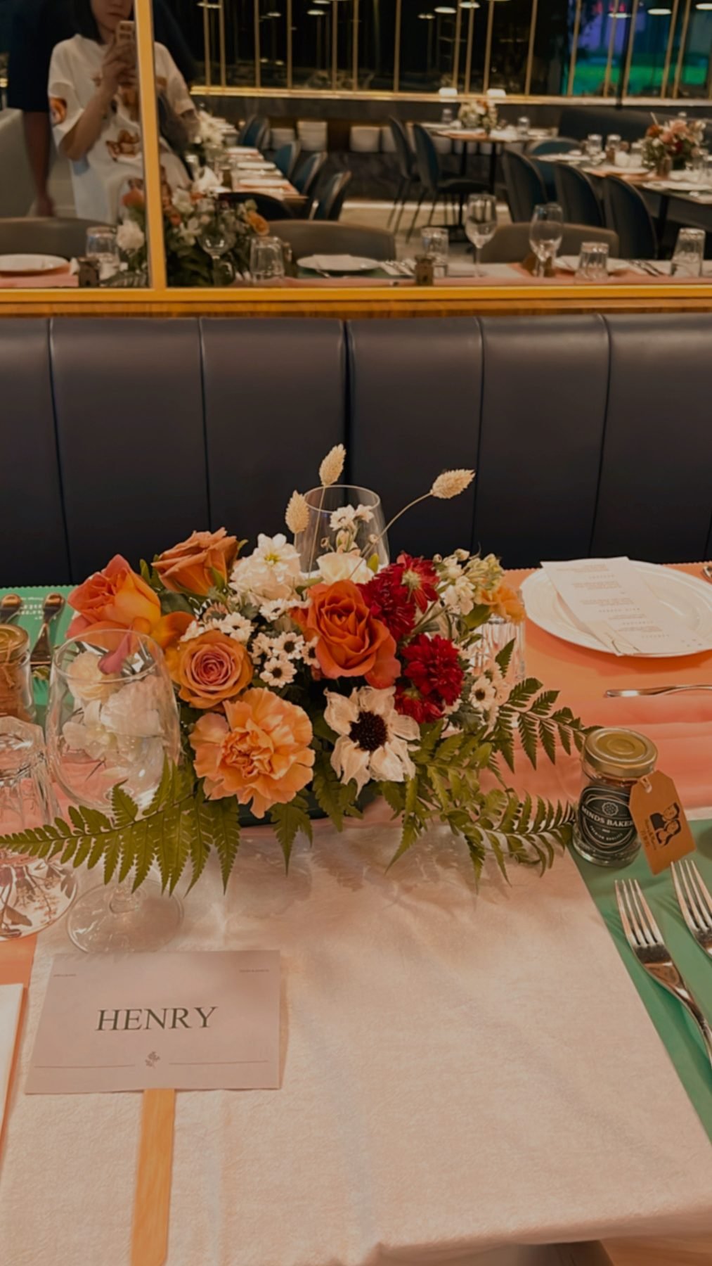 Small rust, orange and white table centrepiece on a set reception place setting
