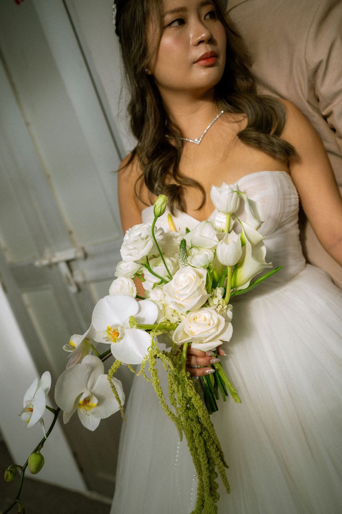 Close detail of a cascading white bouquet with roses, calla lilies, orchids and trailing green amaranthus