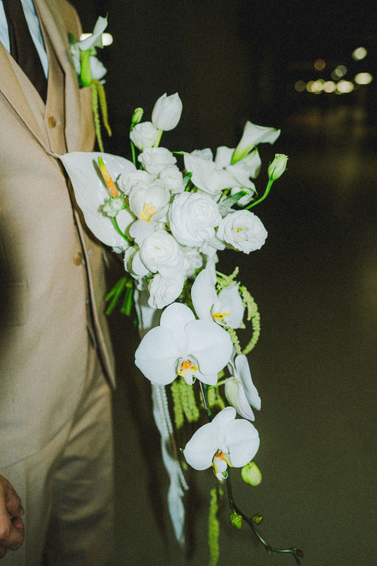 Close detail of the cascading white bouquet with orchids, roses and long green trailing strands