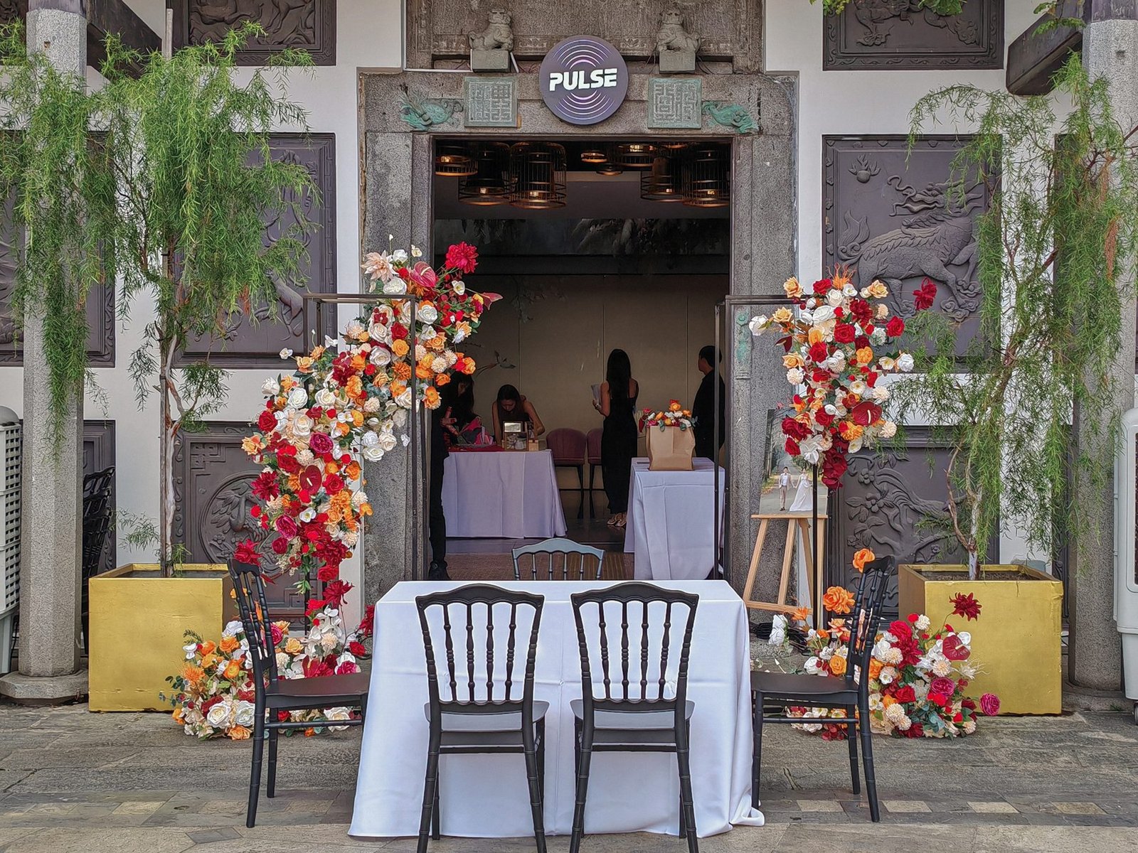 Black frame floral stands flanking an entrance table at an ornate stone doorway