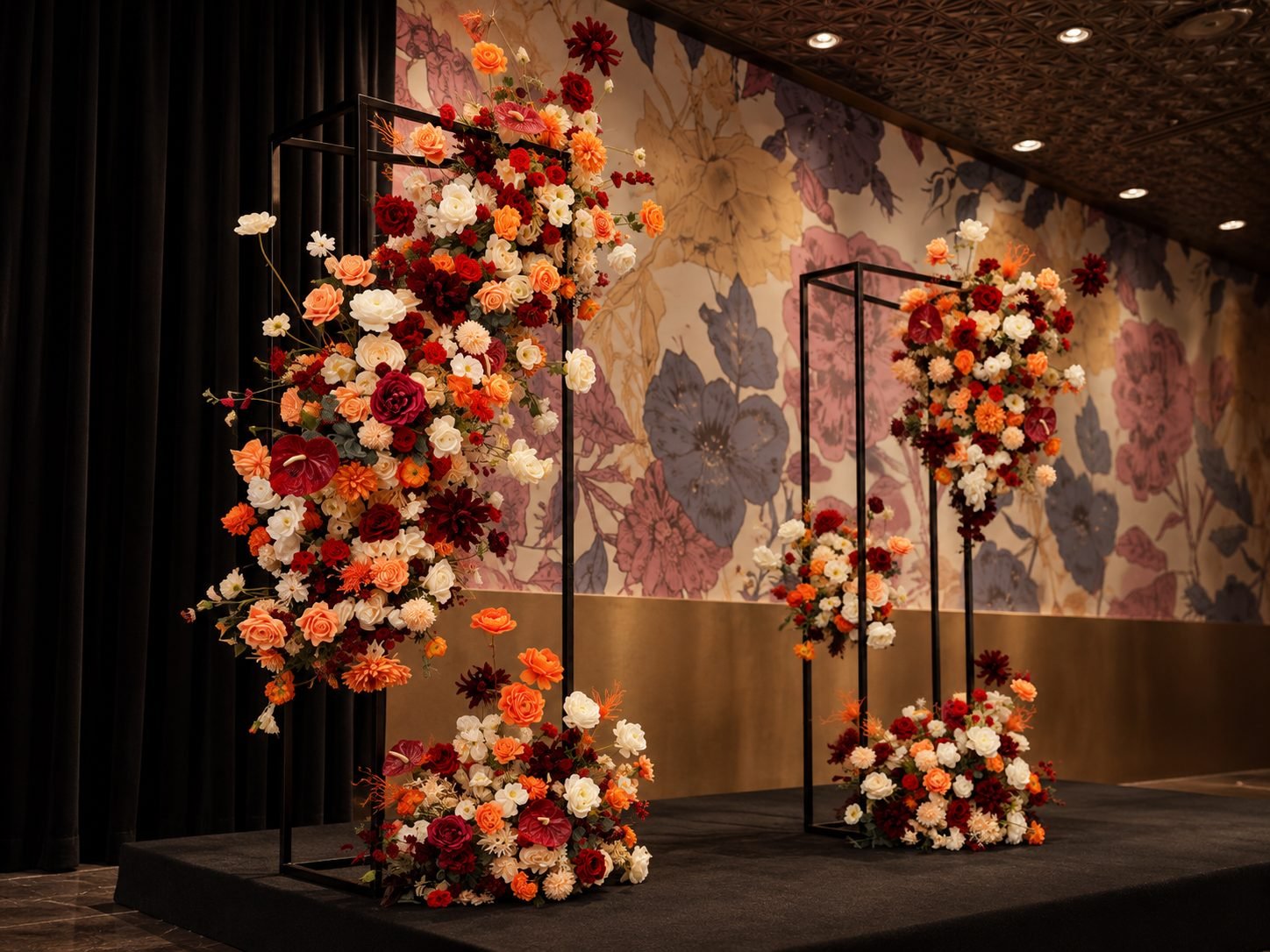 Black frame floral stands on a stage against a floral-print feature wall