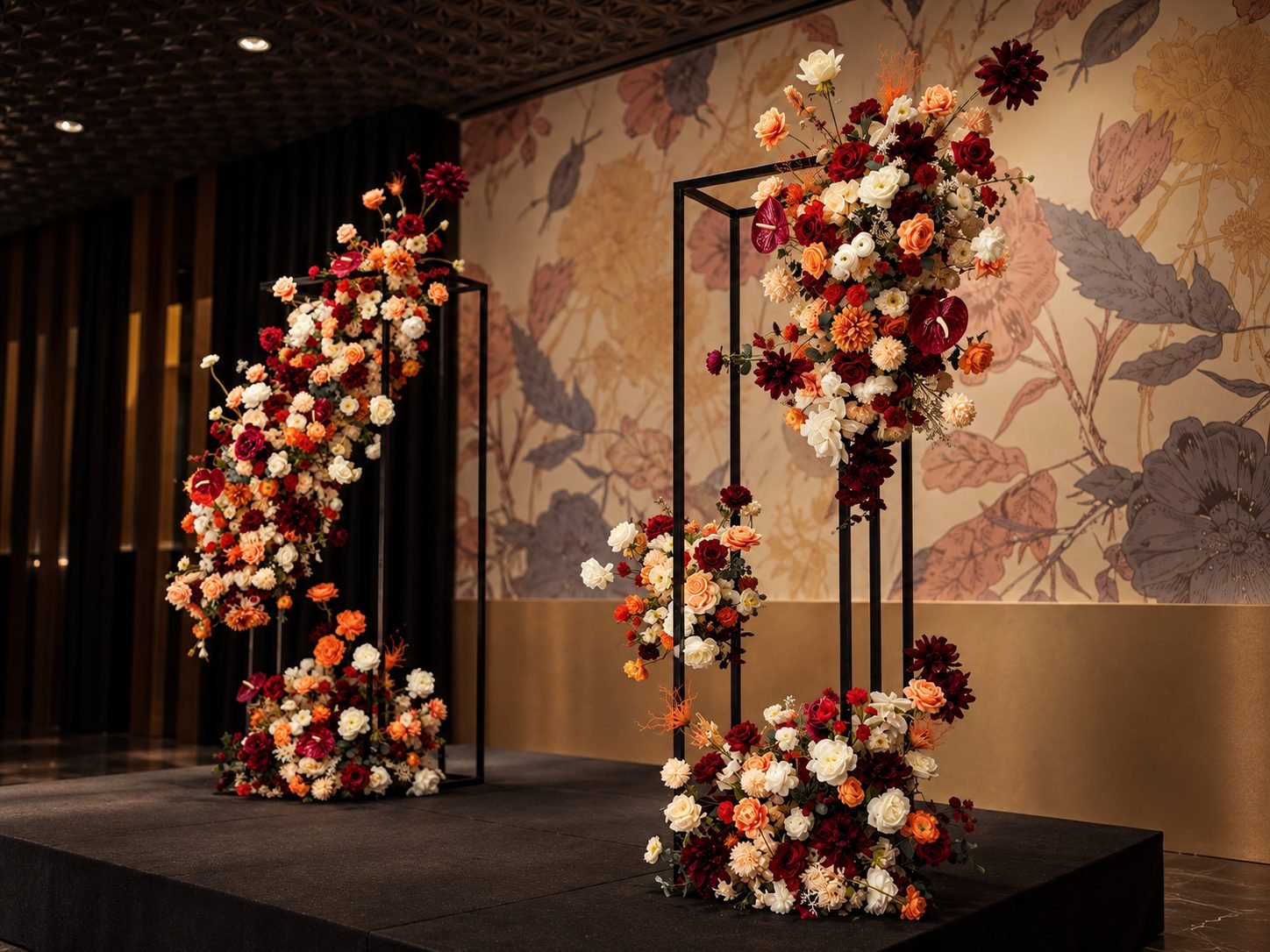 Tall black frame stands dressed in burgundy, apricot and cream cascading flowers