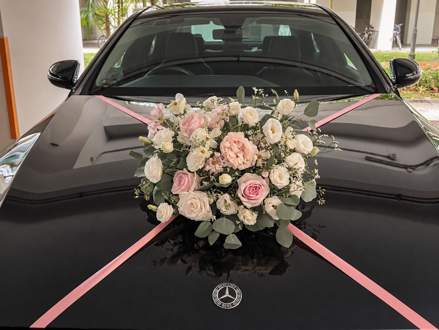 Pink and white rose bonnet flowers tied with ribbon on a black wedding car, from a Church of St Teresa solemnisation